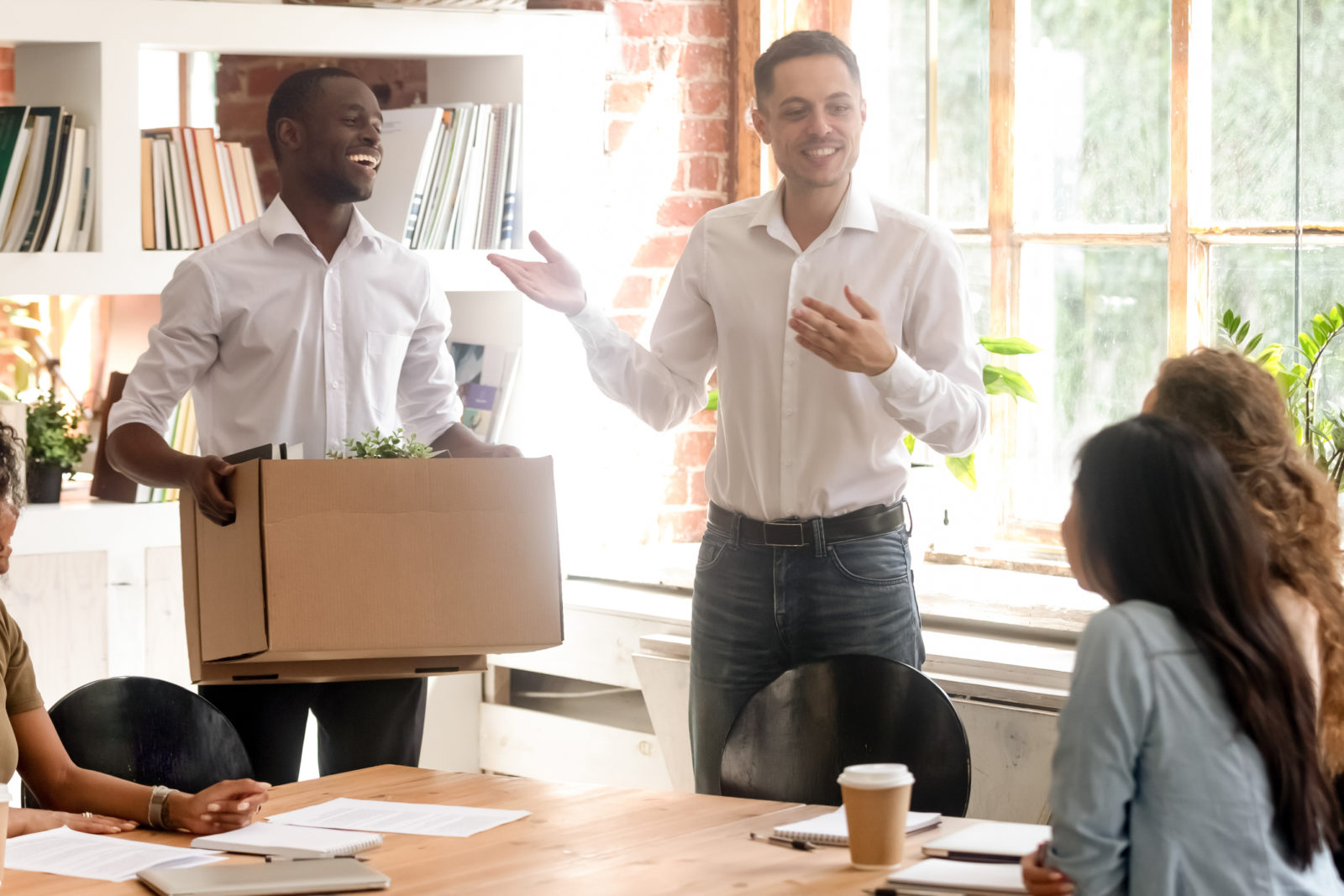 Friendly manager and company staff welcoming happy new african american worker on first work day