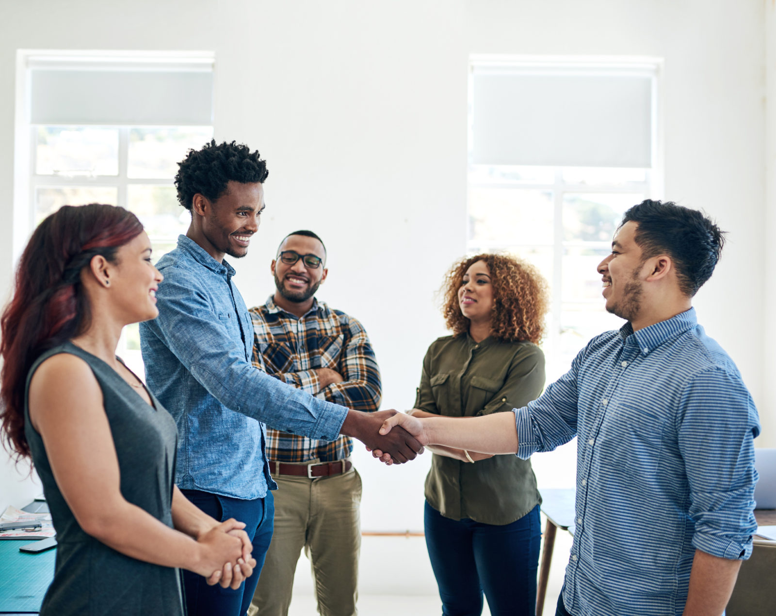 Shot of happy colleagues shaking hands in a modern office